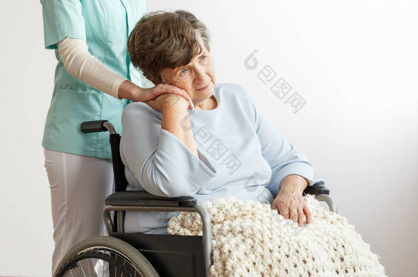 <strong>护士</strong>支持坐在轮椅上的悲伤残疾老年妇女