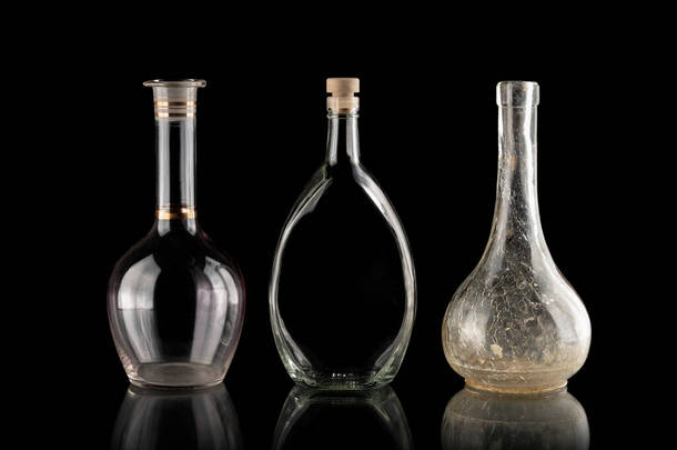 玻璃<strong>器皿</strong>在黑色孤立的背景上.各种形状的酒瓶。一组透明的项目。物体下面的倒影旧的家居用品易碎的盘子。液体容器.