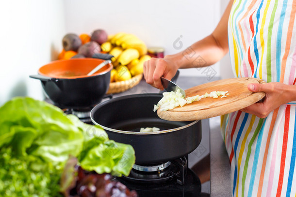 年轻女子在她现代的厨房里做饭 