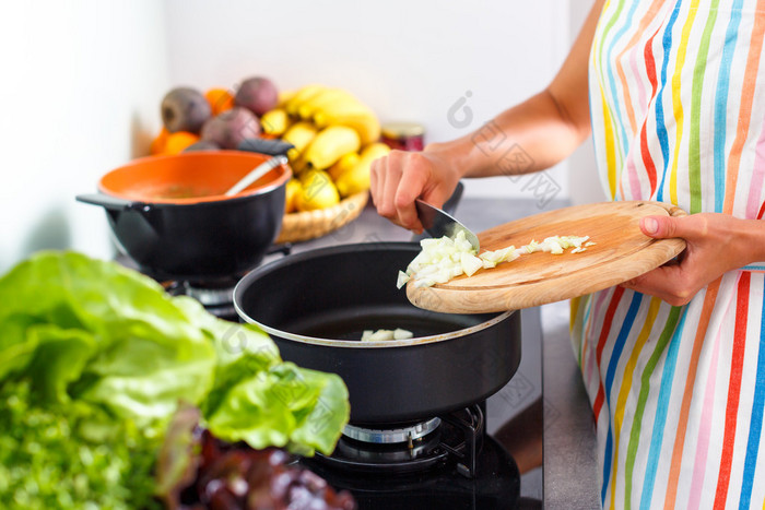 年轻女子在她现代的厨房里做饭 