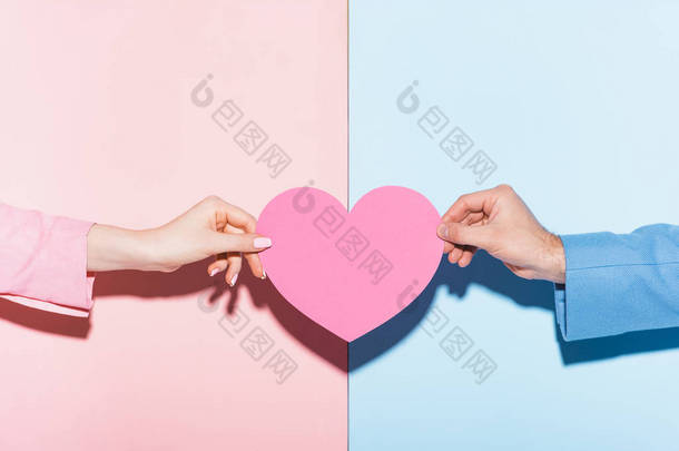 粉色和蓝色背景的男人和女人拿着心形卡片的剪影 