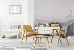 黄色和灰色现代扶手椅和一张白色床在多功能房间内部与山壁纸和木家具