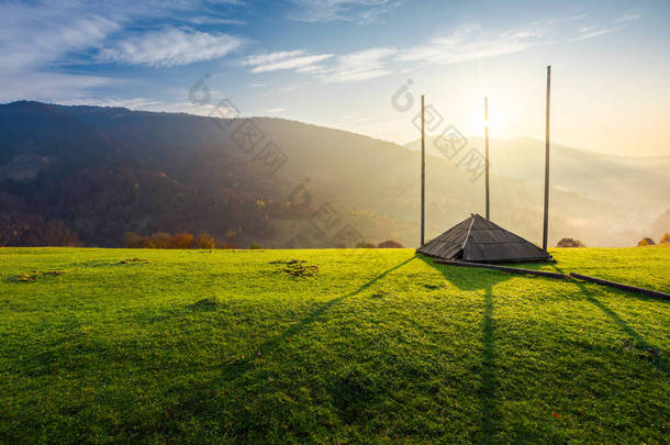日出时, 草地上的山坡上空着干草营房。美丽的雾景色在遥远的山谷。农村生活方式