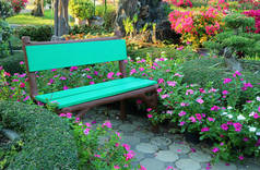 在一丛簇生机勃勃的粉红色花朵中间，有薄荷绿色的木制长椅