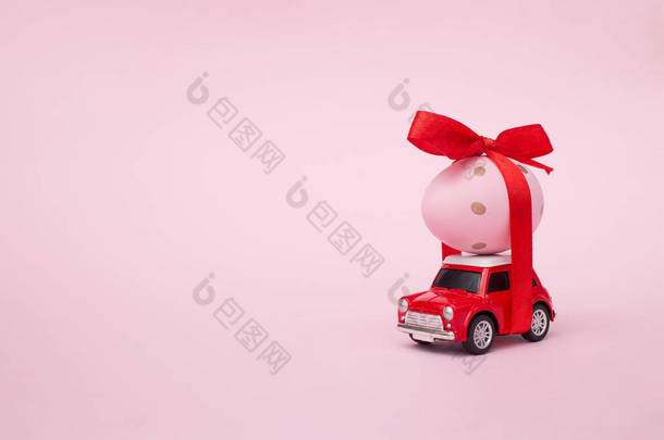 复活节春假的概念，红色玩具车上有鸡蛋，粉红的粉刷背景。复制空间.