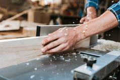 木匠在木匠铺靠近圆锯的地方拿着木板的剪影 