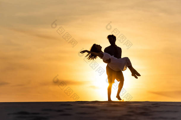 夕阳西下，男人在沙滩上绕着女人旋转的轮廓
