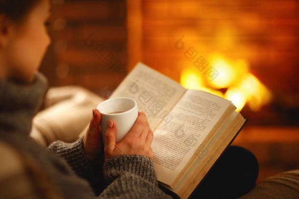 一本书和一杯咖啡在冬天的晚上在女孩的手附近 