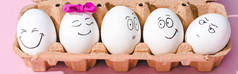 鸡蛋的全景拍摄与不同的脸表情在鸡蛋纸箱上的粉红色