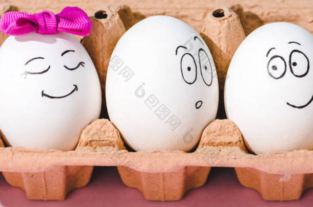 鸡蛋的全景拍摄与不同的脸表情在鸡蛋纸箱上的粉红色