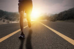 目标与奋斗理念，跑步者在阳光升起的道路上奔跑. 
