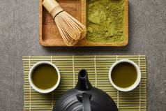 在绿桌垫上用茶和红茶壶的白杯顶视图，靠近竹须和船上的火柴粉