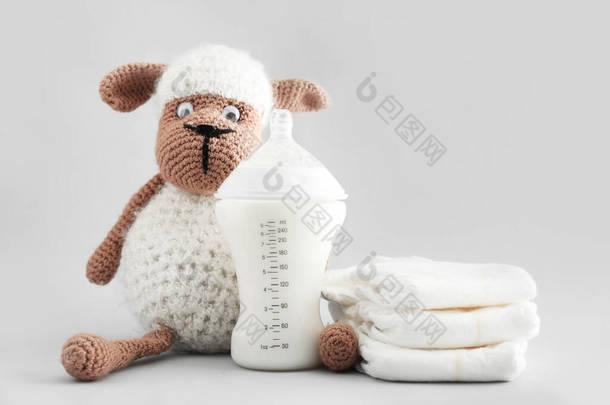 带灰色背景玩具和尿布的婴儿用奶瓶