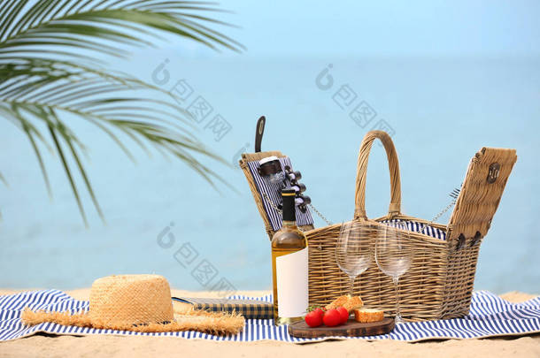 柳条篮上有食物和葡萄酒在靠近大海的毛毯上，文字的空间。 暑期野餐