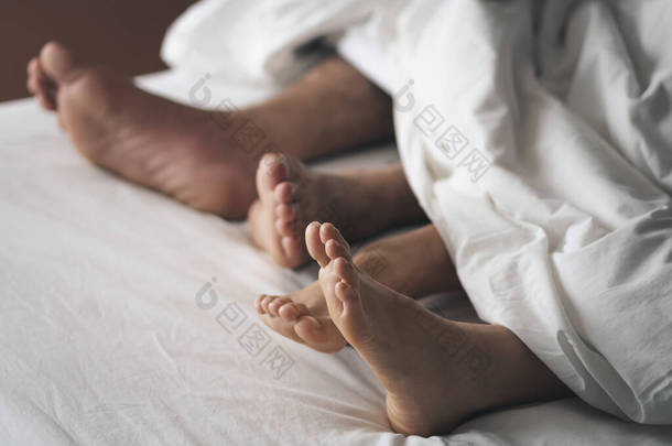 一对夫妇的脚在床上的特写。夫妻之间的爱