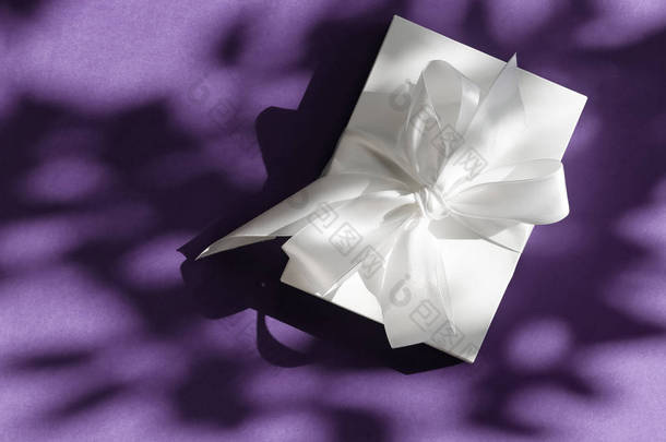 豪华节日白色礼品盒，带丝带，在紫罗兰上鞠躬