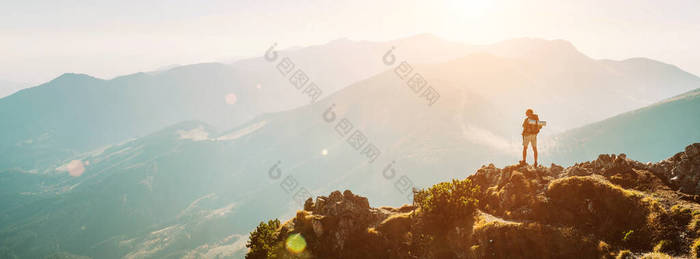 背包小人影的登山健行者，带着美丽的全景呆在山顶上