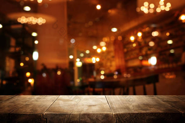 在抽象模糊的餐厅灯光前的木制桌子图像