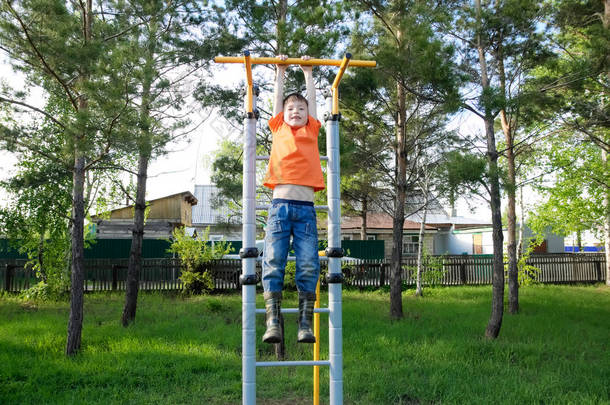 男孩在单杠健身房在户外玩。孩子在操场上，孩子们的活动。开心的孩子。积极健康的童年概念