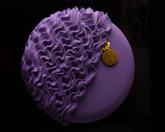 淡紫色圆形慕斯蛋糕，用黑色背景的分子海绵蛋糕装饰，顶部视图