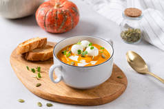 南瓜奶油汤与椰奶，南瓜籽和莫扎拉球的白色混凝土背景。 健康的饮食小吃和午餐。 文字的位置。 侧视图。 菜单、餐厅概念