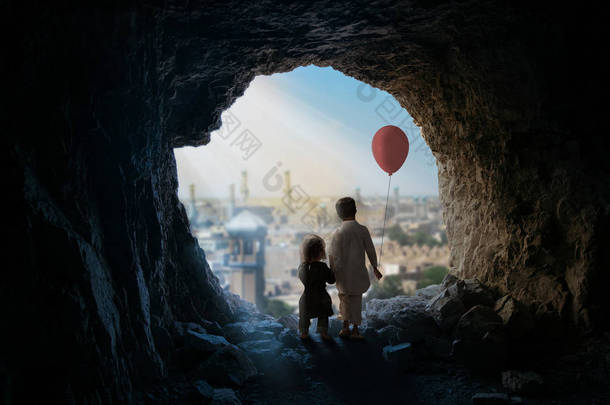 小女孩和男孩与气球站在山洞里