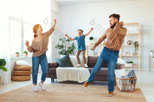 快乐的家庭母亲、父亲和女儿在家里跳舞  