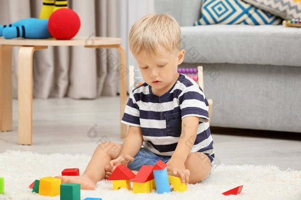 可爱的男孩在地板上玩构造器在家里