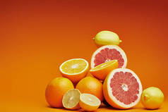 新鲜成熟的整体特写镜头视图和橙色背景上的柑橘切片水果