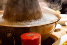 传统的北京风格的中国燃煤火锅，有一个甜甜圈形状的黄铜锅。将生鲜的配料放在饭桌的中心，放在锅子周围.