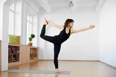 身穿黑色运动服的年轻健身模特在演播室做瑜伽，舞主摆姿势
