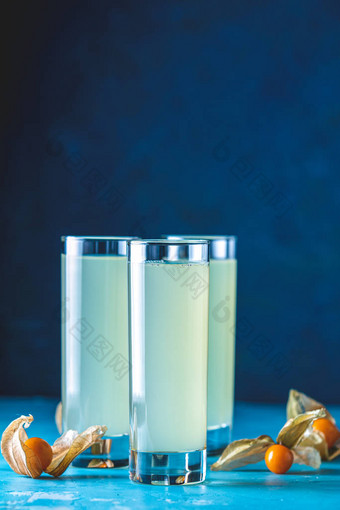 加奥佐、希腊茴香、白兰地或阿拉伯酒精的酒精鸡尾酒在高球玻璃杯中饮用拉基酒、装饰过的白葡萄酒和蓝色混凝土表面的红糖.图片