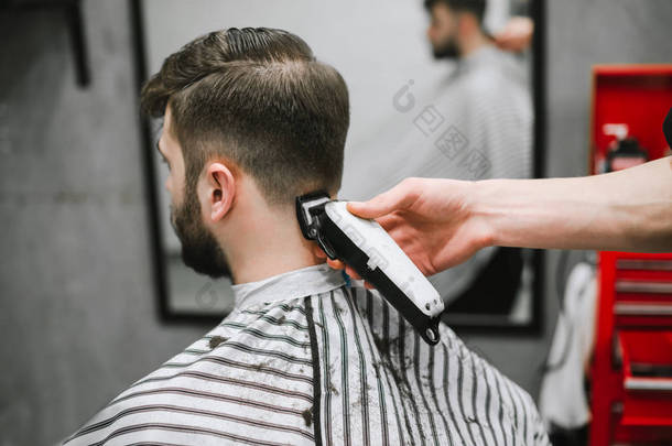 专业男理发师在理发店给留胡子的男人做发型，后视图，理发师的手