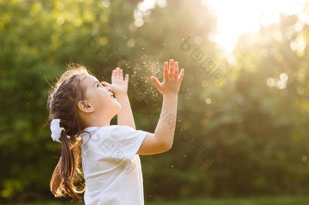 无忧无虑的孩子奔跑和跳跃在绿色夏天草甸捉住肥皂气泡。幸福、童年和自由概念
