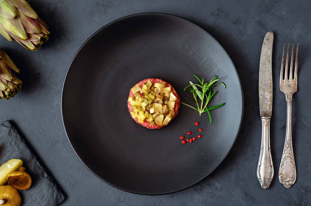 牛肉馅饼配腌制黄瓜和腌制蘑菇在黑色盘子里。黑暗的背景.