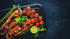 西红柿、 橄榄、 草药和干酪面包法棍。冰冷的小吃。意大利菜。木制的背景.