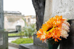 向日葵和白花花束在墓碑上放着一个塑料杯子