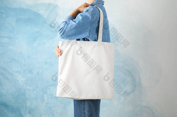 年轻女子拿着手提包在蓝色背景，空间距