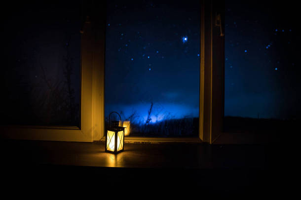 从黑暗的房间透过窗户看到星星的夜景。黑暗房间里的<strong>夜空</strong>, 用古老的老式灯笼从窗户看到。长曝光镜头