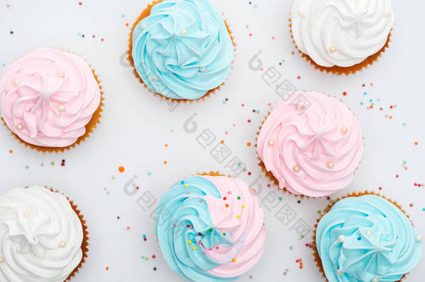 美味的白色，粉红色和蓝色的纸杯<strong>蛋糕</strong>的顶视图，洒在白色上