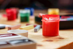 一罐打开的红色油漆在一张木桌上的蜡笔和油漆中.