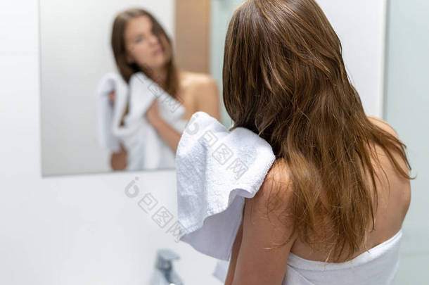 妇女擦湿头发用毛巾在浴室