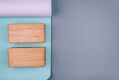 蓝色粉色瑜伽垫和灰色背景的两个木制块的顶部视图。案文的篇幅.