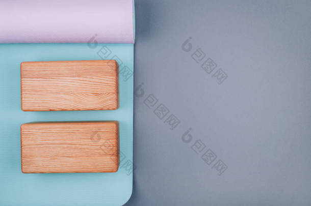 蓝色粉色<strong>瑜伽垫</strong>和灰色背景的两个木制块的顶部视图。案文的篇幅.