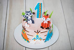 关闭蛋糕从糕点厨师的生日1岁的婴儿。儿童蛋糕上装饰着动物形象、窝布和第一