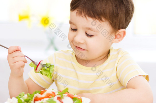 可爱的小男孩吃蔬菜沙拉