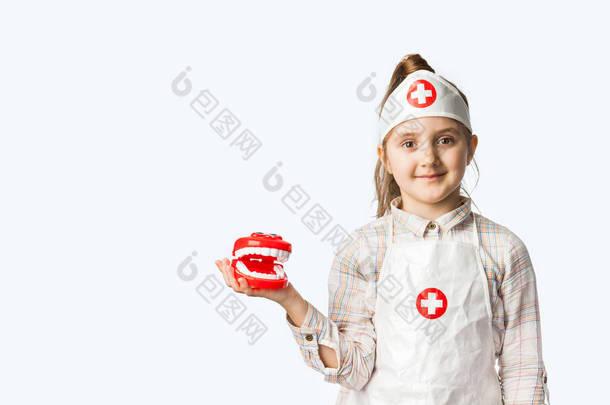 小酷医生牙医女孩在医疗服与玩具下巴和牙刷