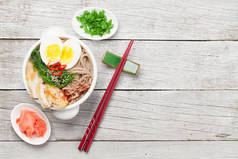 亚洲面条拉面汤，木制背景，配鸡肉、蔬菜和鸡蛋。俯视平面布置图