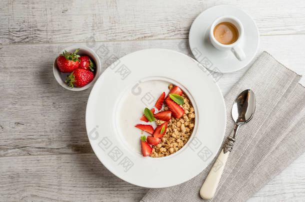 带牛奶的新鲜<strong>草莓</strong>和绿色薄荷叶燕麦片的特写照片在灰色的木桌上放上一杯咖啡