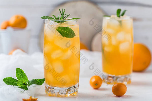 美味橙冰鸡尾酒与金橘和薄荷在白色石头背景  